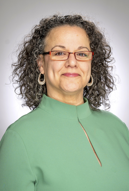 Headshot of Claudine Taaffe, a middle aged black woman with red glasses. She is wearing a bright red scarf and black shirt, and her curly hair is shoulder length.