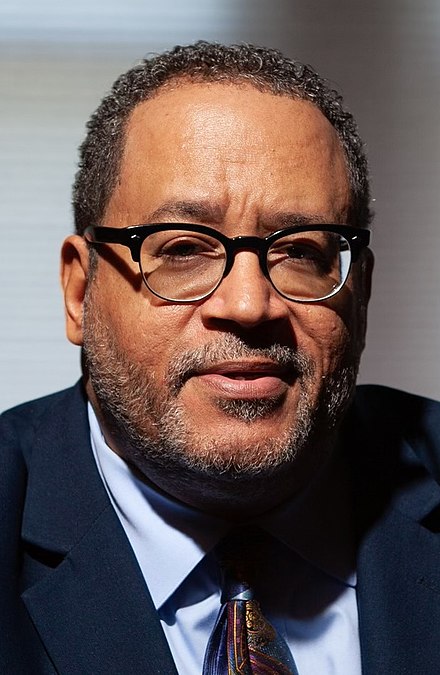 Headshot of Michael Eric Dyson, a middle aged black man with glasses. He is wearing a dark suit, white shirt, and dark tie.