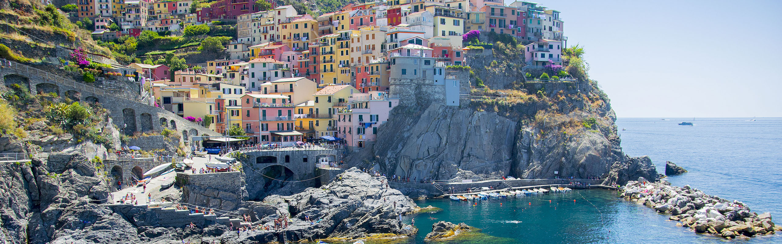 wide shot of Cinque Terre, many colorful houses on a hilltop by the ocean