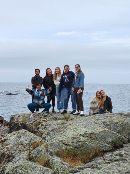 Group of students standing on rocks in front of water