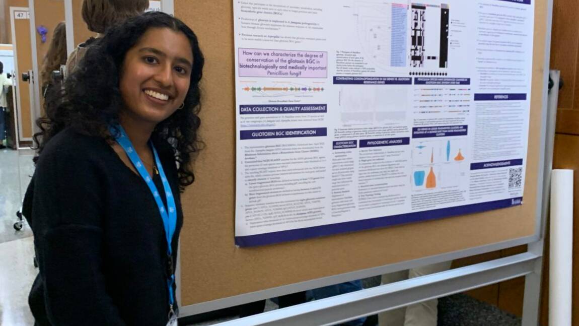 Charu posing beside a poster presentation