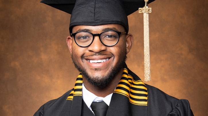 JJ Johnson smiling in graduation cap & gown