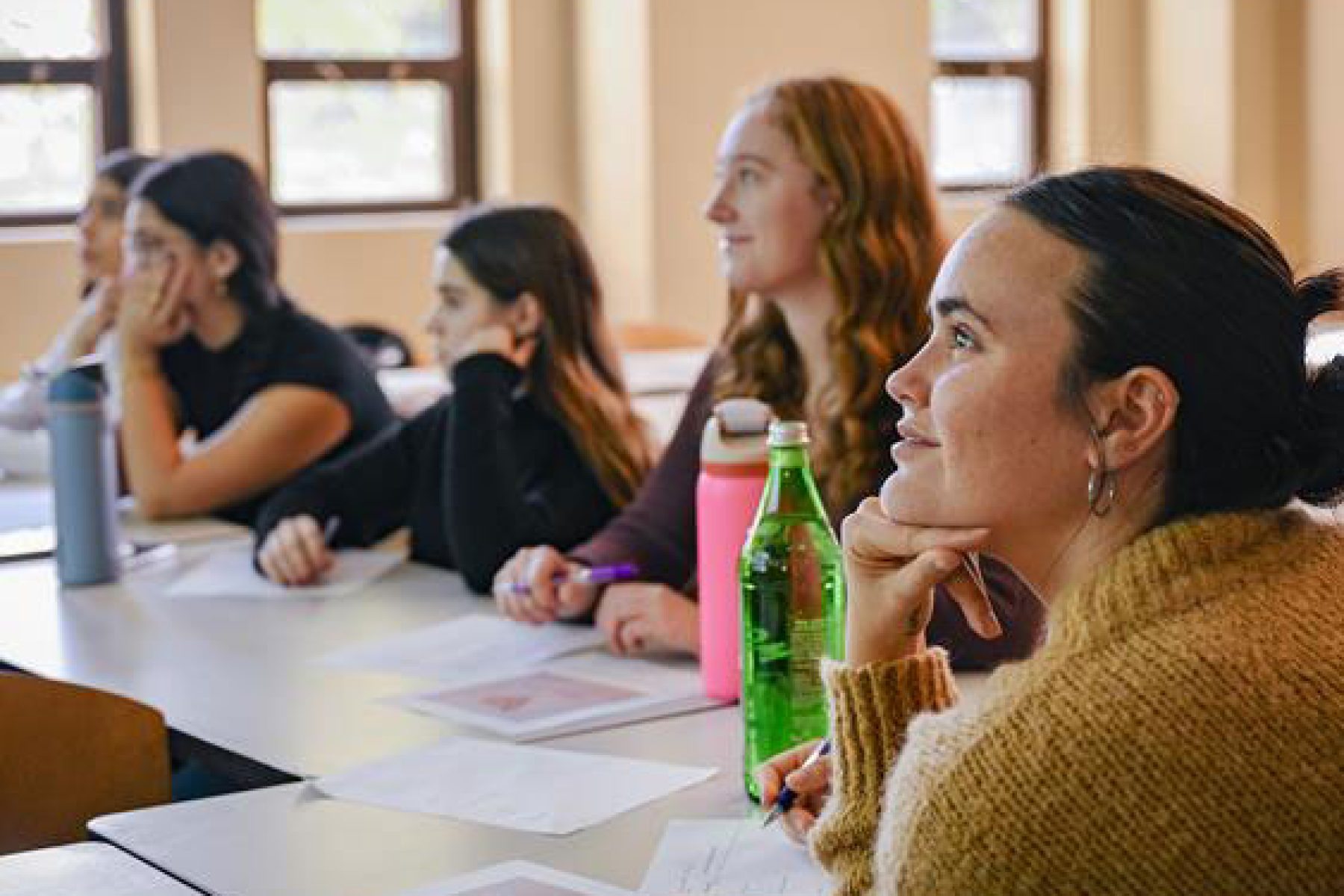 Students sit at a table in a classroom
