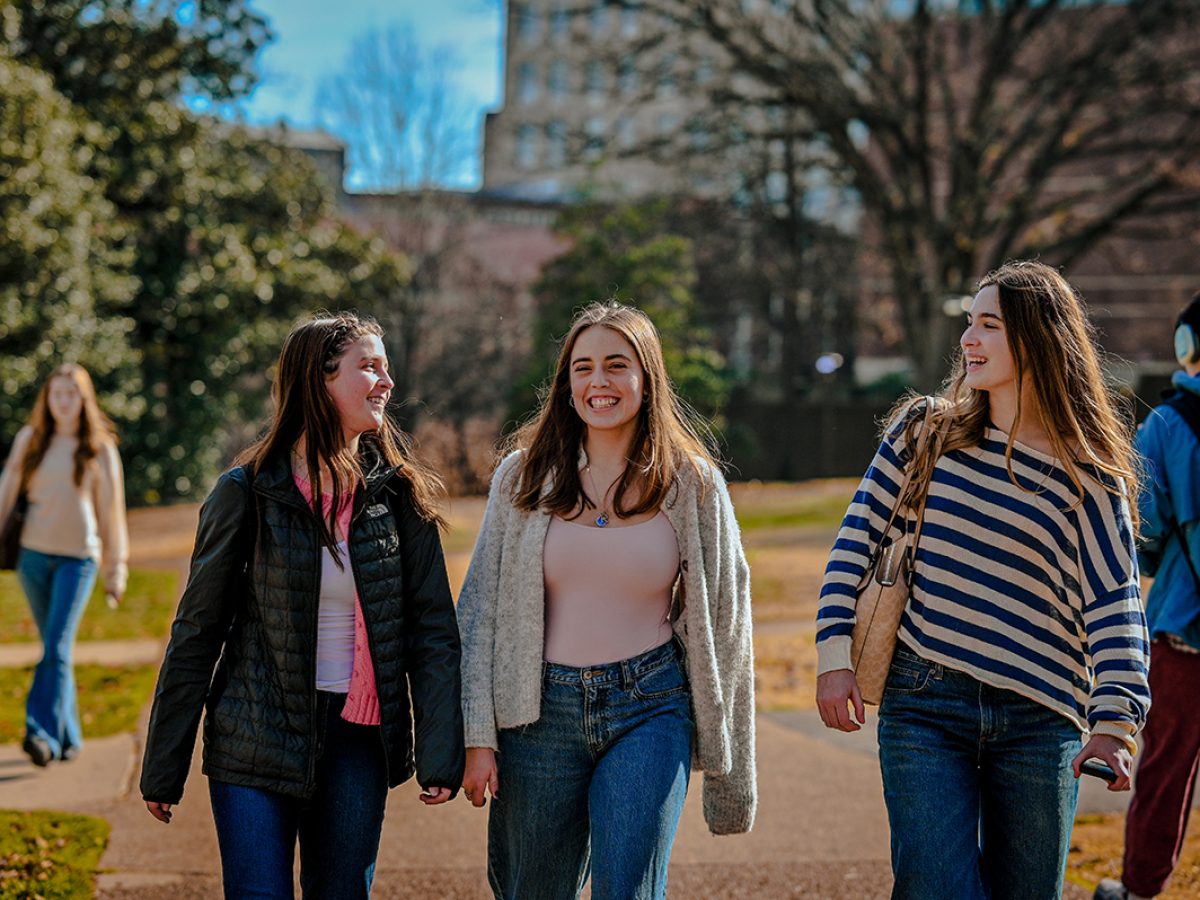 Three female students walking through campus on a sunny day